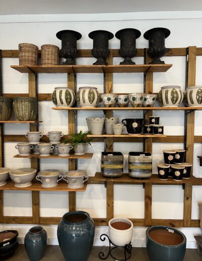Decorative pottery and plant containers displayed on wooden shelves in Pensacola FL